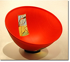 A modern red bowl with a colorful abstract design inside.